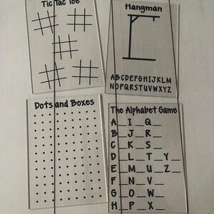 May include: Four clear acrylic game boards with black text. Games include Tic Tac Toe, Hangman, Dots and Boxes, and The Alphabet Game. The Hangman board has the alphabet printed below the gallows.