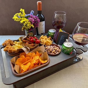 Könnte beinhalten: Graues Holzserviertablett mit verschiedenen Snacks und Getränken. Es enthält gebratenes Hähnchen, Pommes Frites, Chips, Erdnüsse, Tomaten und Weingläser. Eine Flasche Rotwein und zwei Bierdosen sind ebenfalls vorhanden.