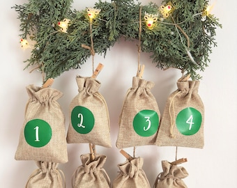 May include: A Christmas advent calendar made of burlap bags with numbers 1 through 8 hanging from a green garland with white lights.