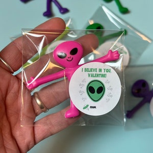 May include: A pink alien-shaped stretchy toy with a sticker that says "I believe in you, Valentine!" from [name].