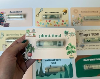 Może przedstawiać: Prostokątna karta z napisem plant fund, ilustracjami roślin doniczkowych oraz przezroczystym plastikowym blistrem zawierającym zwinięty banknot. Karta ma kremowe tło z zielonym tekstem i grafikami roślinnymi.