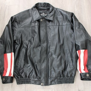 May include: Black leather jacket with red and white stripes on the sleeves. The jacket has a zipper closure and a collar. The label on the jacket reads "Oscar Pieu, Genuine Leather, Made in USA."