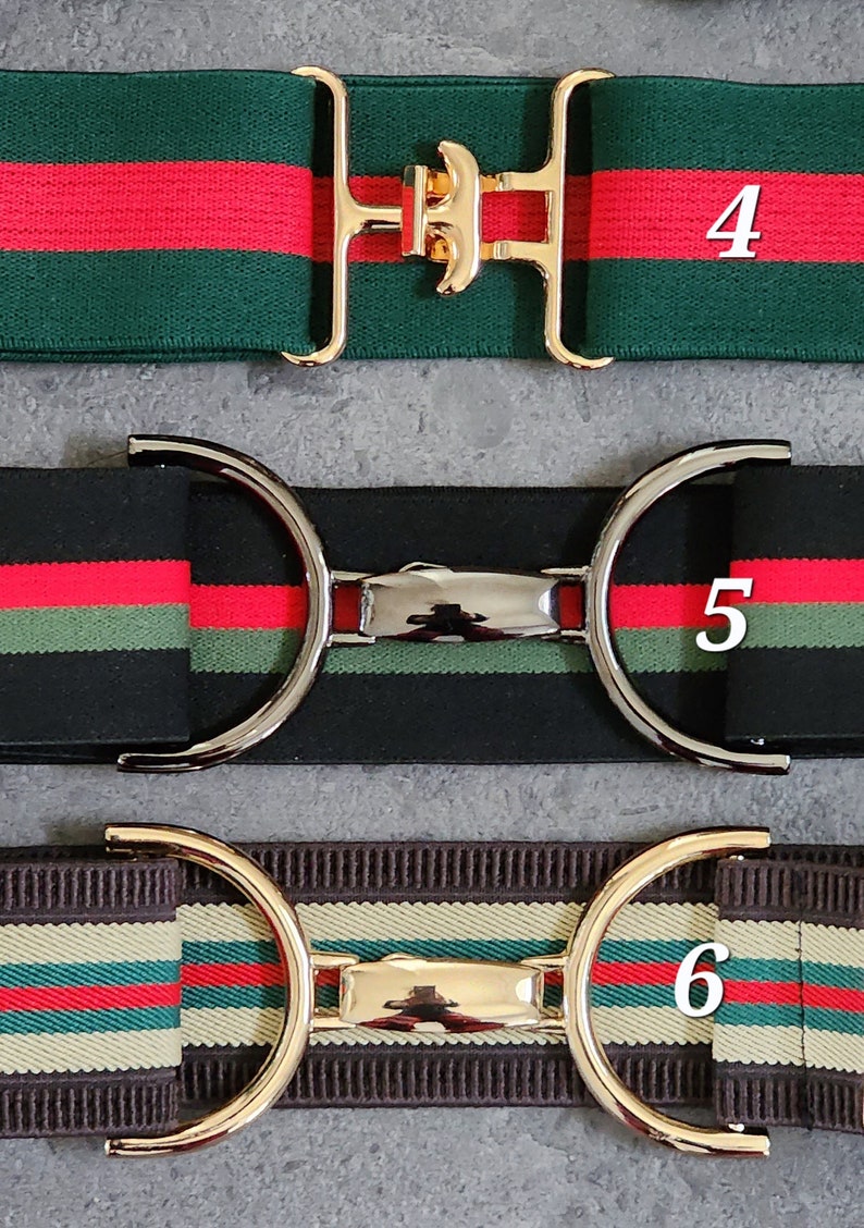 Pode incluir: Tr&ecirc;s cintos el&aacute;sticos com listras de cores diferentes e estilos de fivela diferentes. O cinto superior &eacute; verde e vermelho com uma fivela dourada. O cinto do meio &eacute; preto e vermelho com uma fivela prateada. O cinto inferior &eacute; castanho e bege com uma fivela dourada. Os cintos s&atilde;o numerados 4, 5 e 6.