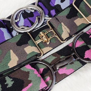 May include: Three elastic belts with different camouflage patterns and metal buckles. The belts are black, green, and pink with a camouflage pattern. The buckles are silver, gold, and black.