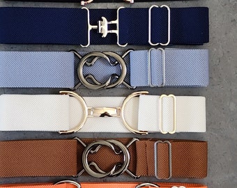 Pode incluir: Seis cintos elásticos com diferentes tecidos coloridos e fivelas de metal. As fivelas têm a forma de um freio de cavalo, um oito e um círculo. Os cintos têm todos 2,5 cm de largura.