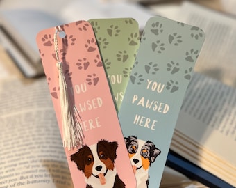 Peut inclure: Trois marque-pages colorés avec des empreintes de pattes et le texte "You Pawsed Here". Chaque marque-page présente un dessin animé de chien australien.