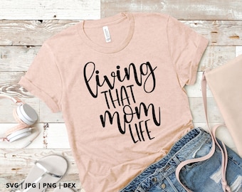 May include: A pink t-shirt with the text "living that mom life" in black script font.