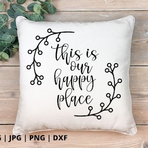 以下が含まれることがあります： 黒い文字で「This is our happy place」と書かれた白いクッションと、黒い花の模様が描かれています。