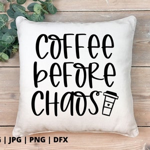 Op de afbeelding: Een wit kussen met zwarte tekst die "Coffee Before Chaos" luidt en een zwart koffiekopje-icoon.
