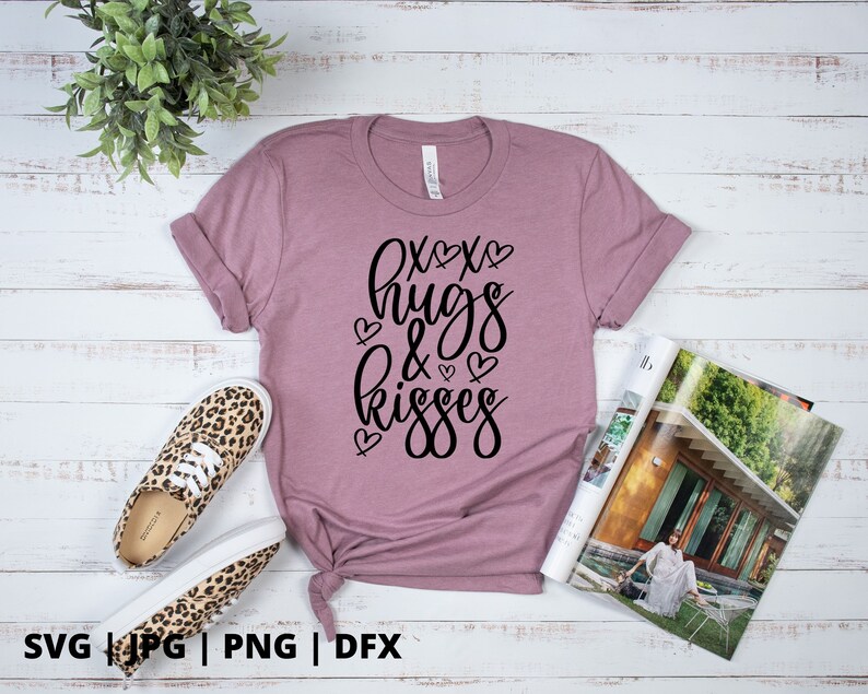K&ouml;nnte beinhalten: Ein mauvefarbenes T-Shirt mit dem Text "XOXO hugs & kisses" in schwarzer Schrift mit kleinen Herzen um den Text.