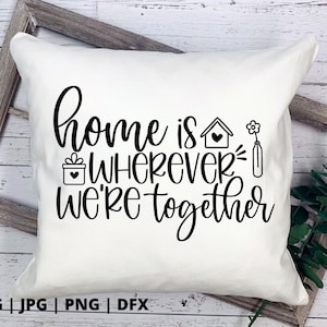 May include: White throw pillow with black text that reads "home is wherever we're together". The text is in a cursive font. There are small black and white illustrations of a house, a gift box, and a flower.