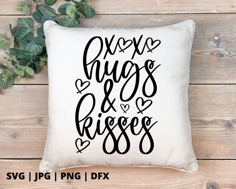 K&ouml;nnte beinhalten: Ein wei&szlig;es Kissen mit schwarzem Text, der "oxox hugs & kisses" lautet, mit kleinen Herzen um den Text herum.
