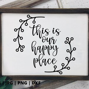 以下が含まれることがあります： 「This is our happy place」と書かれた、黒い文字と花の模様が描かれた白い看板です。