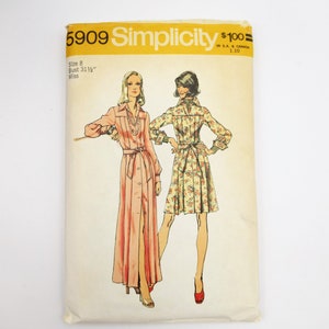 May include: Vintage Simplicity sewing pattern number 5909 for a dress. The pattern is for a size 8, bust 31 1/2 inches, and is for a miss. The pattern shows two women wearing different versions of the dress. One dress is a long, pink dress with a button-up front and a tie belt. The other dress is a shorter, floral dress with a button-up front and a tie belt.