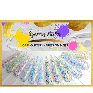 May include: Ayanna's Parlor opal glitter press-on nails. The nails are iridescent and have a variety of colors and shapes.
