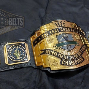 May include: A gold and black championship belt with the text "BEST BELTS CHAMPIONSHIP" at the top. The belt has multiple plates with text including "TFC THE FORE COURSE SERIES" and "MVP". The belt also has the text "JUST TAP IT IN GIVE IT A LITTLE TAP TAP TAPAROO GILMORE".