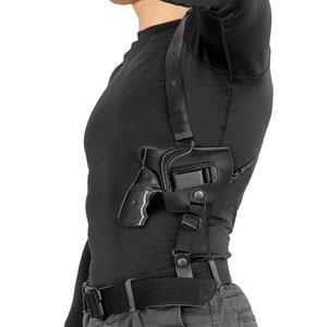 May include: A black leather shoulder holster with a black handgun. The holster has an adjustable strap and a snap closure.
