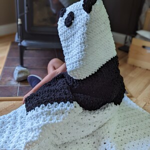 Puede incluir: Una manta con capucha de oso panda hecha a mano. La manta es blanca con detalles negros, formando la cara y las orejas del panda. La suave y acogedora manta est&aacute; dise&ntilde;ada para ser usada, ofreciendo calidez y comodidad.