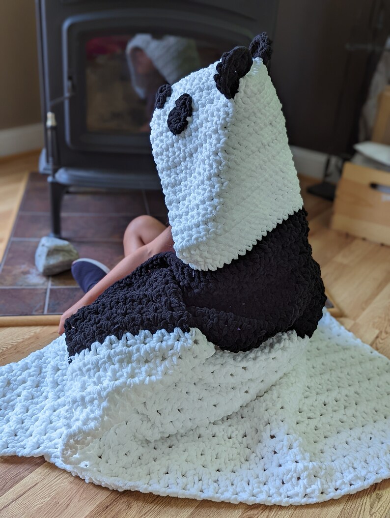 Puede incluir: Una manta con capucha de oso panda hecha a mano. La manta es blanca con detalles negros, formando la cara y las orejas del panda. La suave y acogedora manta est&aacute; dise&ntilde;ada para ser usada, ofreciendo calidez y comodidad.