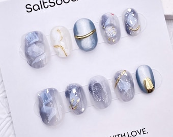 Unghie finte fatte a mano con effetto tie-dye glitterato: occhio di gatto azzurro, ovale corto