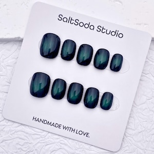 May include: A set of dark teal press-on nails with a glossy finish. The nails are arranged on a white card with the text "SaltSoda Studio" and "HANDMADE WITH LOVE."