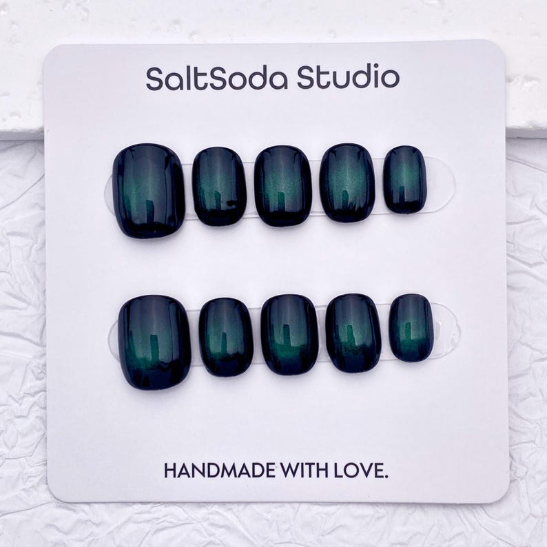 May include: A set of press-on nails in a dark teal color with a glossy finish. The nails are arranged on a white card with the text "SaltSoda Studio" and "HANDMADE WITH LOVE."