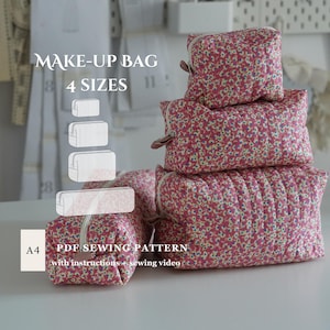 May include: Four quilted make-up bags in different sizes, adorned with a pink floral design. The bags are rectangular with a zip closure and a small handle. The image includes the text "MAKE-UP BAG 4 SIZES" and "PDF SEWING PATTERN".