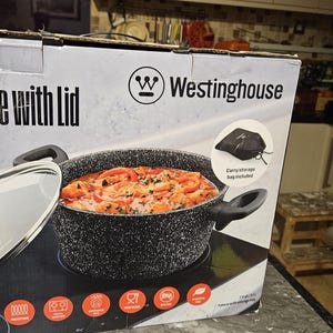 May include: A black casserole dish with a lid, featuring a speckled finish. The dish is filled with a red sauce and vegetables. The box reads "7.5 qt / 7.1 L Casserole with Lid" and "Westinghouse".