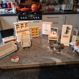 May include: A collection of miniature dollhouse furniture, including a sofa, TV, cabinet, chair, and vanity. The pieces are made of wood and painted in neutral colors. A small decorative item is also present.