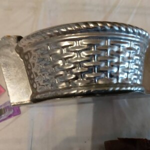May include: A silver metal mold shaped like a basket with a woven pattern. The mold is designed for baking.