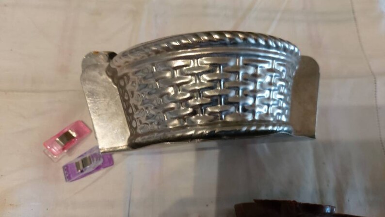 May include: A silver metal mold shaped like a basket with a woven pattern. The mold is designed for baking.