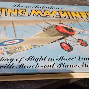 May include: A book cover featuring the title "Those Fabulous Flying Machines" and an illustration of a vintage aircraft. The book is a history of flight with a punch-out plane model.