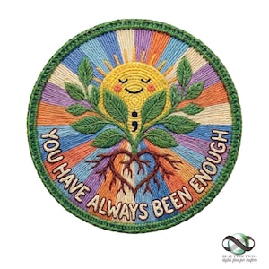 Pode incluir: Remendo bordado com um sol amarelo sorridente, folhas verdes e um sistema radicular em forma de coração. O texto "YOU HAVE ALWAYS BEEN ENOUGH" está arqueado ao redor do desenho. O remendo tem uma borda verde e um fundo listrado colorido.