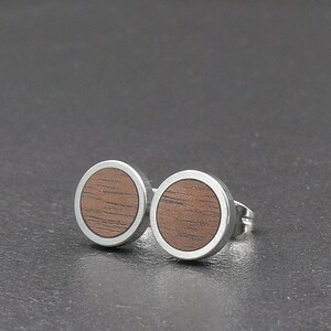 May include: A pair of round wood and silver earrings. The earrings have a silver rim and a brown wood centre.