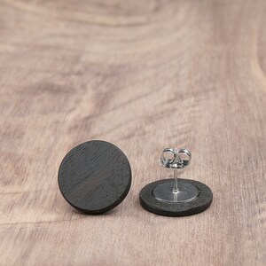May include: A pair of black wood stud earrings with silver posts and backs.
