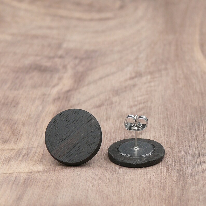 May include: A pair of black wood stud earrings with silver posts and backs.