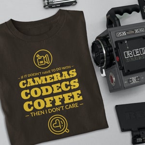 May include: A brown t-shirt with a yellow graphic that says "If it doesn't have to do with cameras, codecs, coffee, then I don't care."  The graphic also includes a small camera icon and a coffee cup icon.