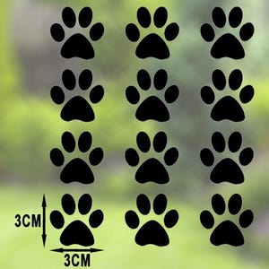 May include: Black paw print decals, each measuring 3cm by 3cm, arranged in a grid pattern. The image shows a collection of paw prints, ideal for pet lovers. The background is a blurred green and white.