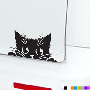 May include: Black cat decal, depicting a cartoon cat peeking over a surface. The cat has large eyes, whiskers, and pointed ears. The decal is designed for application to a car or other smooth surface.
