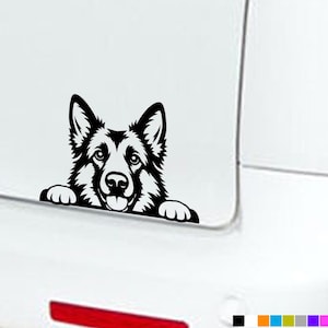 Könnte beinhalten: Ein schwarzer Vinyl-Aufkleber mit einer stilisierten Illustration eines Deutschen Schäferhund-Kopfes, dessen Vorderpfoten so positioniert sind, als würde er über eine Kante schauen. Das Design nutzt kräftige Linien für Gesichtszüge.