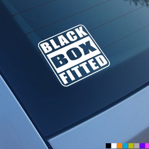 Puede incluir: Una pegatina cuadrada de vinilo blanco con esquinas redondeadas aplicada en la ventana de un coche. El adhesivo presenta el texto BLACK BOX FITTED en letras blancas mayúsculas y negritas dispuestas en tres líneas dentro de un marco.