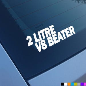 May include: White vinyl sticker with the text "2 Litre V8 Beater" on a blue car window.