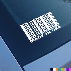 Peut inclure: Autocollant en vinyle blanc avec un code-barres et le texte "MADE IN USA" sur une vitre de voiture bleue.