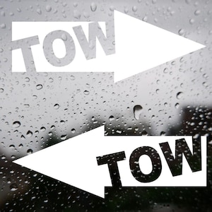Puede incluir: Dos flechas blancas con la palabra "TOW" en letras negras en una ventana de lluvia.
