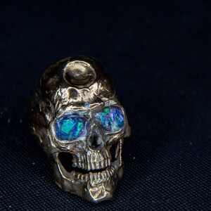 silver skull ring based on argus panoptes the greek one hundred eyed cyclops crushed opal set eyes glowing in blacklight