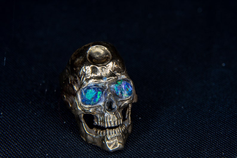 silver skull ring based on argus panoptes the greek one hundred eyed cyclops crushed opal set eyes glowing in blacklight