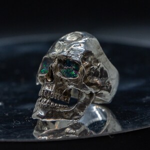 silver skull ring based on argus panoptes the greek one hundred eyed cyclops crushed opal set eyes three quarter view