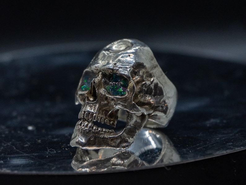 silver skull ring based on argus panoptes the greek one hundred eyed cyclops crushed opal set eyes three quarter view