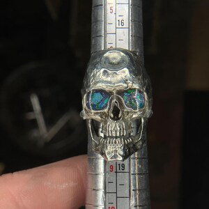 silver skull ring based on argus panoptes the greek one hundred eyed cyclops crushed opal set eyes three quarter front view