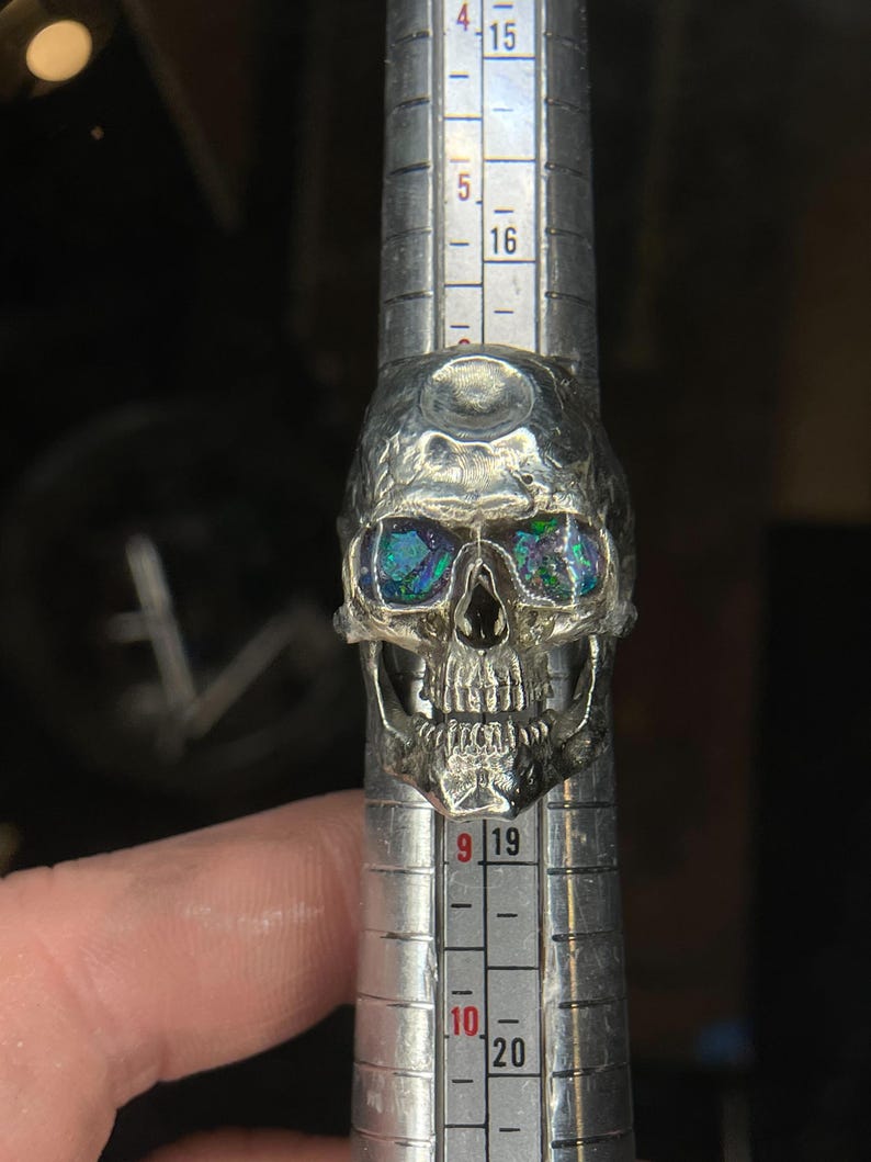 silver skull ring based on argus panoptes the greek one hundred eyed cyclops crushed opal set eyes three quarter front view